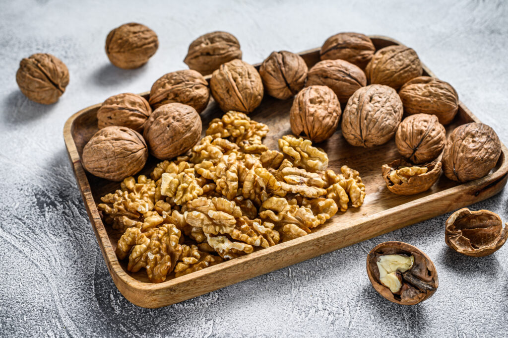 walnuts in a wooden plate and walnut kernels gray 2022 01 19 00 07 51 utc