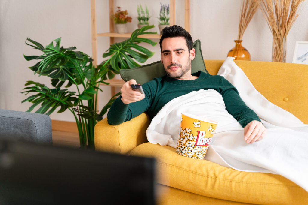 cheerful man watching tv and eating popcorns in li 2023 11 27 05 21 00 utc